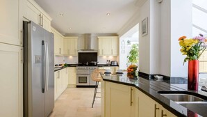 A modern kitchen with light-colored cabinets, a stainless steel refrigerator, a gas stove, and a large window. - 4 Bed in Christchurch (oc-87836) (Christchurch)