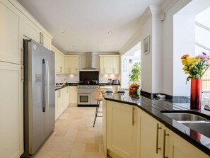 Eine moderne Küche mit hellen Schränken, einem Edelstahlkühlschrank, einem Gasherd und einem großen Fenster.