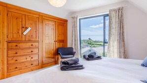 Une chambre avec une grande fenêtre, une armoire en bois et une chaise.