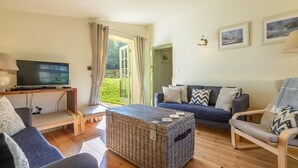 A living room with a TV, sofa, chairs, a coffee table, and a view of a garden. - 3 Bed in King's Lynn (oc-kt097) (Ingoldisthorpe)