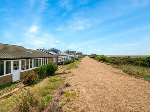Uma fileira de casas com um caminho de cascalho que leva ao mar.