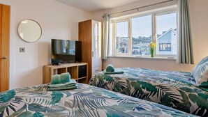 A bedroom with a TV, a window with a view, and a bed with a leaf-patterned bedspread. - 3 Bed in Bideford (oc-90319) (Westward Ho!)