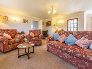 A living room with floral-patterned sofas, a wooden coffee table, and a chandelier. - 2 Bed in Weasenham (oc-kt103) (Weasenham)