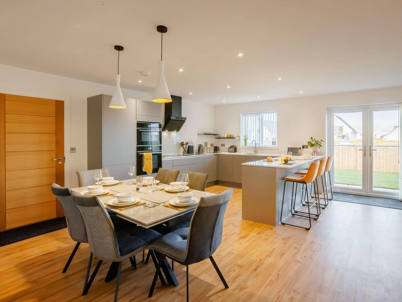 A modern kitchen with a dining area, a bar, and a sliding glass door to a backyard.