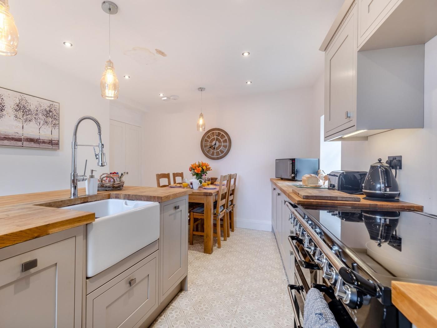 A modern kitchen with a central island, built-in oven, and a dining area with chairs and a table.