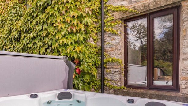Een bubbelbad met een stenen muur en een raam op de achtergrond.