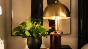 Ein Nachttisch aus Holz mit einer Topfpflanze und einer Tischlampe.