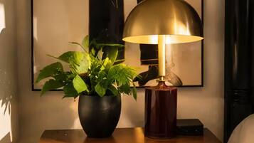 A wooden nightstand with a potted plant and a table lamp.