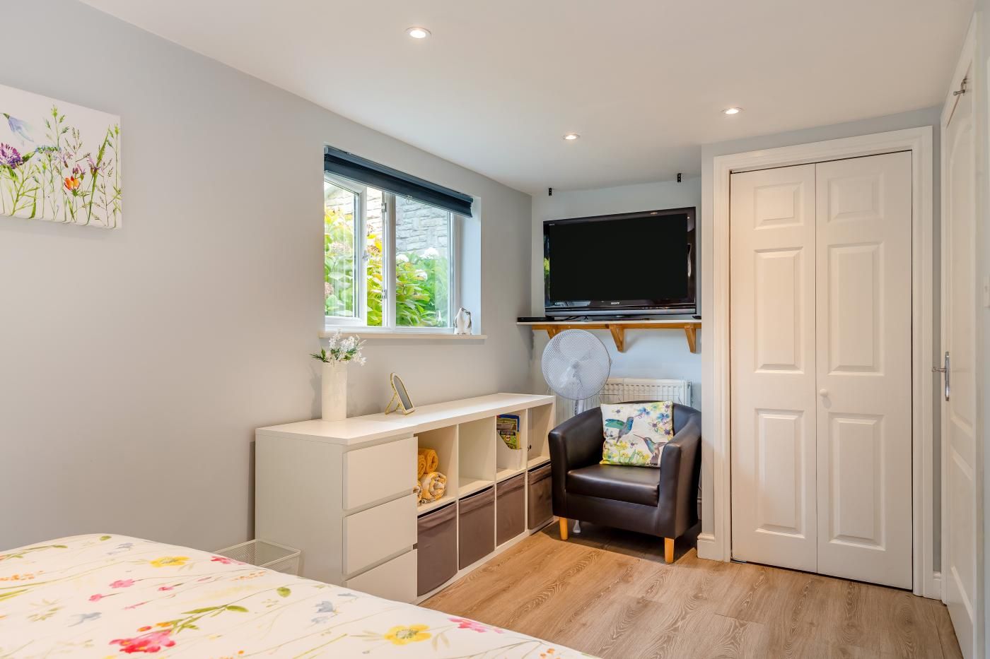 Ein Schlafzimmer mit einem Bett, einem Schreibtisch, einem Sessel, einem Fernseher und einem Kleiderschrank.