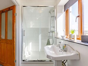 A bathroom with a glass-enclosed shower, a white sink, and wooden doors. - 1 Bed in Lydney (oc-43724) (Lydney)