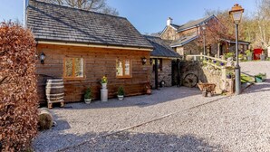 A rustic wooden building with a gravel driveway, stone walls, and a small wooden staircase. - 1 Bed in Lydney (oc-43724) (Lydney)