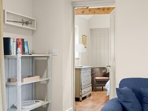 Ein Zimmer mit Bücherregal, Kommode, Stuhl und einem blauen Sofa.