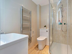 Een moderne badkamer met een douchecabine van glas, een wit toilet en een bad.