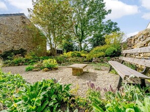 Ein Garten mit einer Steinmauer, einer hölzernen Bank und verschiedenen Pflanzen.