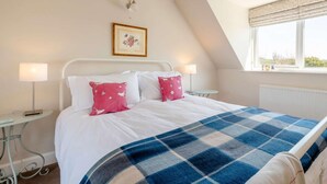 A bedroom with a bed, two bedside tables, a nightstand, a window with a view, and a wall-mounted light fixture. - 2 Bed in Kippford (oc-81129) (Colvend)