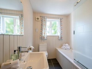 Une salle de bain équipée d’un lavabo, de toilettes, d’une baignoire et d’une fenêtre avec des rideaux.