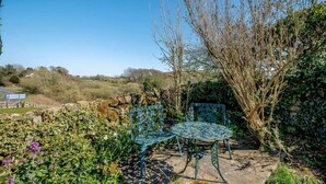 A garden patio with a stone wall, a metal table, and two metal chairs. - 2 Bed in Kippford (oc-81129) (Colvend)