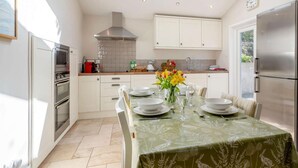 A modern kitchen with skylights, a dining area with a table set for four, and a refrigerator. - 2 Bed in Kippford (oc-81129) (Colvend)