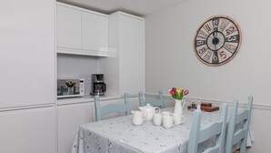 A kitchen with white cabinets, a microwave, and a coffee maker. There is a table with a white tablecloth and a clock on the wall. - 2 Bed in Brecon (oc-bn436) (Brecon)