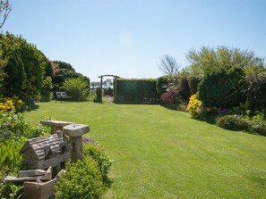 Ein gepflegter Garten mit Rasenfläche, einem Steinbauwerk und einer Holzpergola.