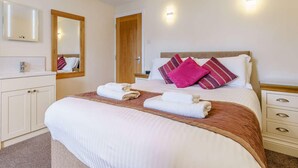 Ein Hotelzimmer mit einem Bett, einem Schminktisch mit Spiegel und einer Tür.