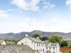 A residential area with houses, a clear sky, and mountains in the background. - 3 Bed in Keswick (oc-83170) (Keswick)