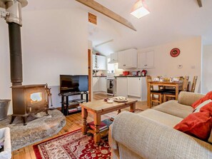 A cozy living room with a fireplace, a television, and a dining area with a table and chairs. - 1 Bed in Penzance (oc-ivban) (Saint Buryan)