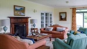 Una sala de estar con chimenea, dos sofás, una mesa de centro y una ventana con cortinas.
