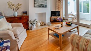 Ein Wohnzimmer mit Sofa, Couchtisch, Fernseher und Blick ins Freie.