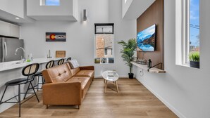 A modern kitchen with a dining area, a sofa, and a view of the outside. - Rino Private Rooftop  - Art District Location. Walk To Everything! (Denver)