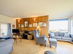 A living room with a fireplace, a television, and a sofa. - 4 Bed in Scourie (oc-ca399) (Scourie More)
