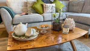 A living room with a sofa, a coffee table with tea set, a vase with flowers, and a framed picture on the wall. - 2 Bed in York (oc-81052) (Helmsley)