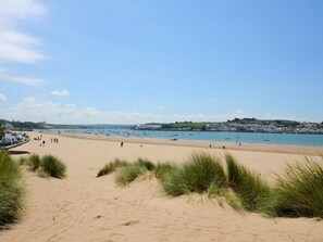 Een strand met duinen en een heldere lucht.