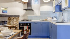 A modern kitchen with blue cabinets, a gas stove, an oven, a sink, and pendant lighting. - 2 Bed in Brixham (oc-bx087) (Brixham)