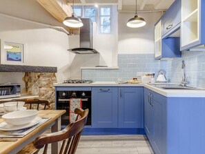 Eine moderne Küche mit blauen Schränken, einem Gasherd, einem Backofen, einer Spüle und Pendelleuchten.