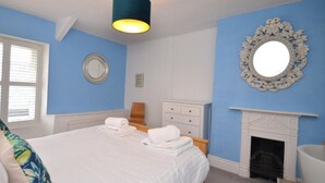 A bedroom with a bed, a mirror, a fireplace, and a window. - 2 Bed in Brixham (oc-bx087) (Brixham)