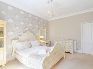 Une chambre à coucher avec un lit, une commode, un miroir et un lustre.