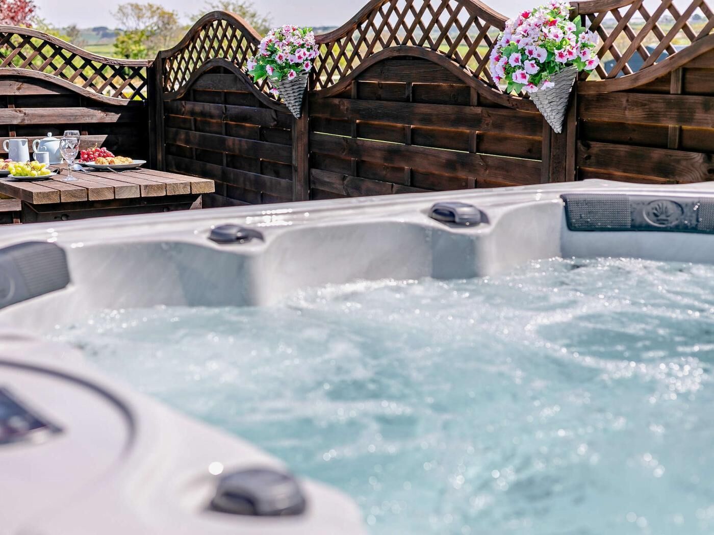 Un jacuzzi con cerramiento de madera y cestas de flores.