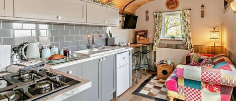 Una cocina compacta con estufa a gas, pileta y heladera pequeña.