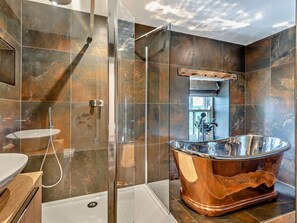Une salle de bain moderne dotée d’une douche à parois de verre, d’une baignoire sur pieds et d’un meuble-lavabo avec un vasque.