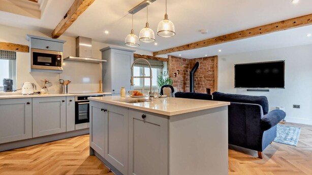 Une cuisine moderne dotée d’un îlot central, d’un four à micro-ondes encastré et de luminaires suspendus.