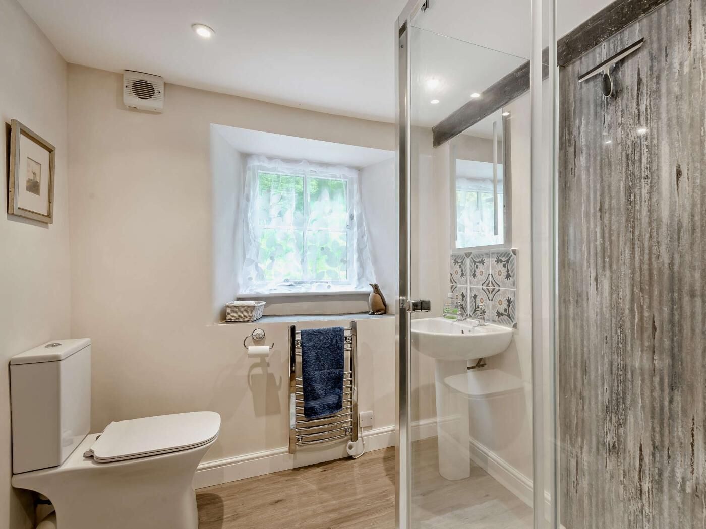 Une salle de bain comprenant des toilettes, un lavabo, une douche en verre, une fenêtre avec vue et un porte-serviettes.