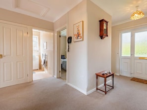 A hallway with a door leading to a bedroom, a small table with a lamp, and a wall-mounted telephone. - 3 Bed in Christchurch (oc-94605) (Bransgore)