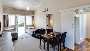 A compact room with a bed, a desk, and a dining area.