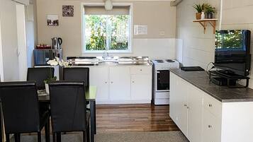 Una cocina compacta con armarios blancos, estufa y un comedor con sillas.