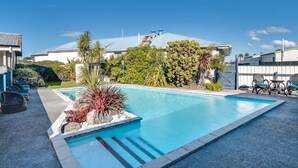 A swimming pool with a clear blue water, surrounded by a landscaped garden with various plants and trees.