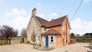 A two-story stone house with a blue door, a stone archway, and a gravel driveway. - 5 Bed in Bicester (oc-87367) (Chesterton)