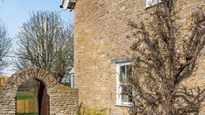 A stone building with a wooden door, a window, and a tree in front. - 5 Bed in Bicester (oc-87367) (Chesterton)
