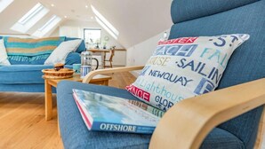 Ein gemütliches Wohnzimmer mit einem blauen Sofa, einem Holztisch und einem Buch mit dem Titel 'OFFSHORE'.