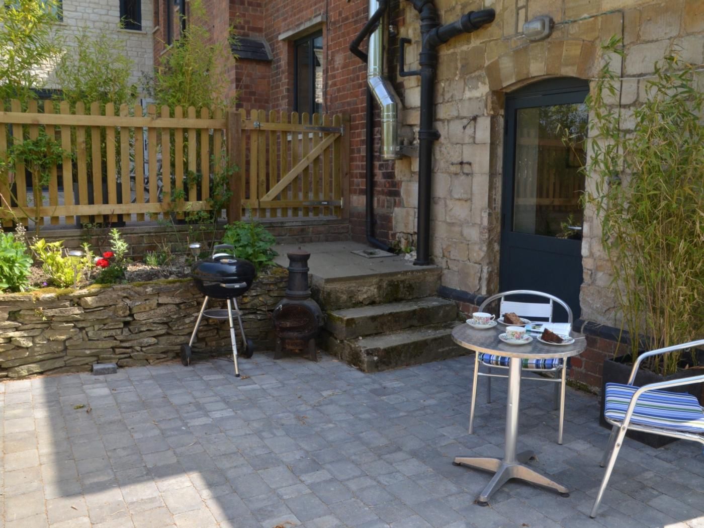Une terrasse avec un barbecue, une table et des chaises, et un mur en pierre.
